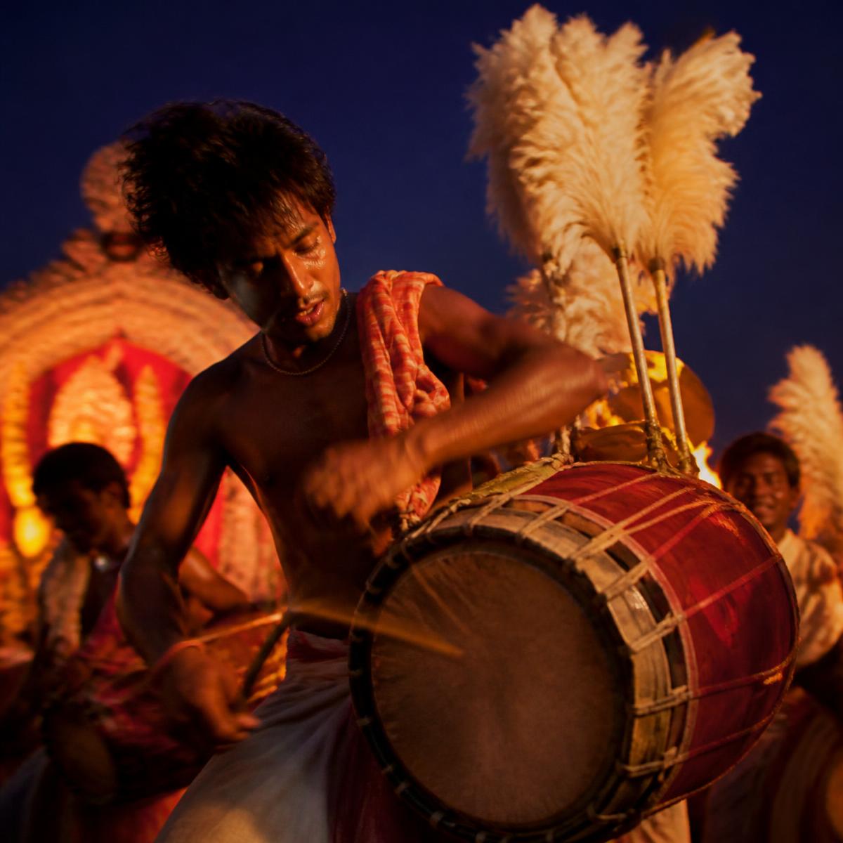 Dhaki playing the dhak with feather plumes during Durga Puja